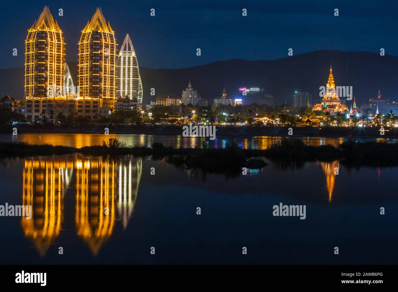 Jinghong, China - 2. Januar 2020: Große Goldene Pagode auch als Dajin-Pagode bezeichnet, die über den Mekong Fluss und die Hotels in der Nähe reflektiert Stockfoto