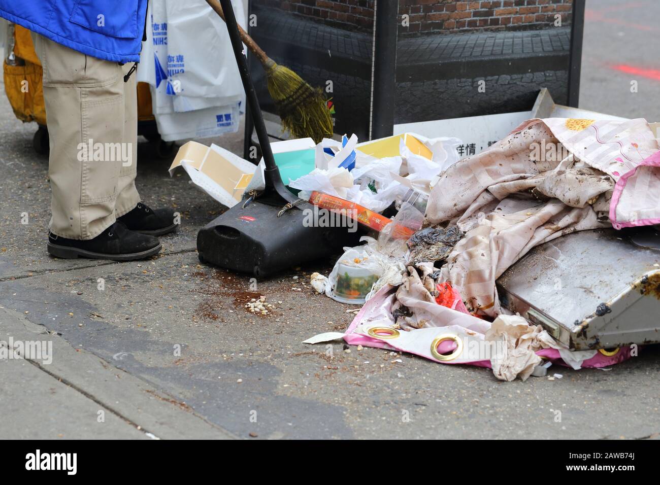 Eine Person mit einem Besen und einer Staubpfanne, die Müll aufräumt, wurde an einer Straßenecke in New York City verschüttet Stockfoto