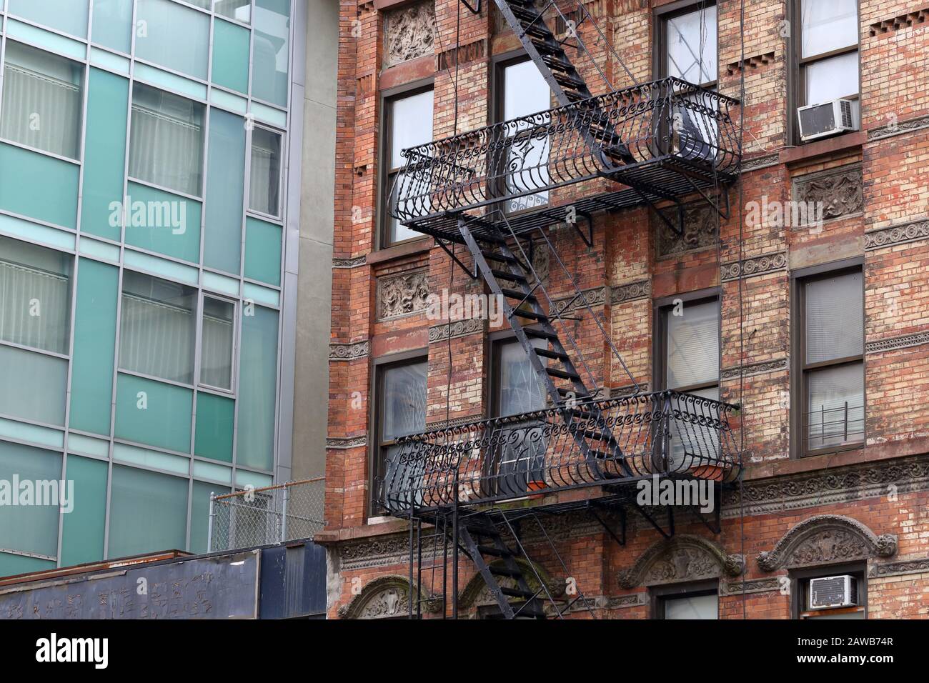 Ein Mietshaus in New York City neben einem modernen Glas- und Stahlgebäude. Stockfoto