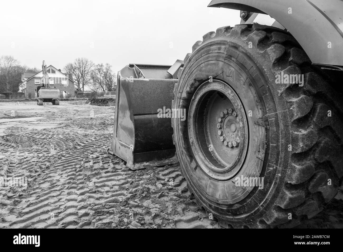 Auf einer Baustelle befindet sich ein orangefarbener Bagger, der den Boden auf Fundamente vorbereitet Stockfoto