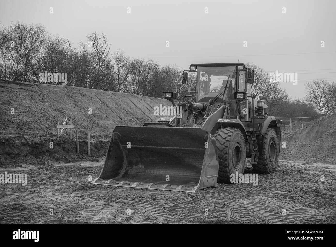 Auf einer Baustelle befindet sich ein orangefarbener Bagger, der den Boden auf Fundamente vorbereitet Stockfoto
