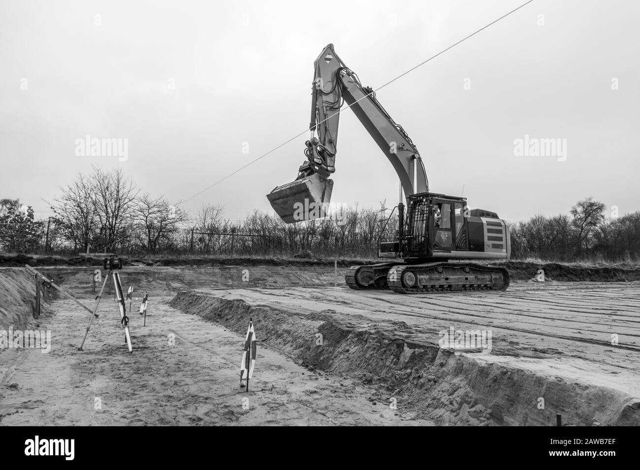 Auf einem Baugelände befindet sich ein gelber Bagger, der den Boden auf Fundamente vorbereitet Stockfoto