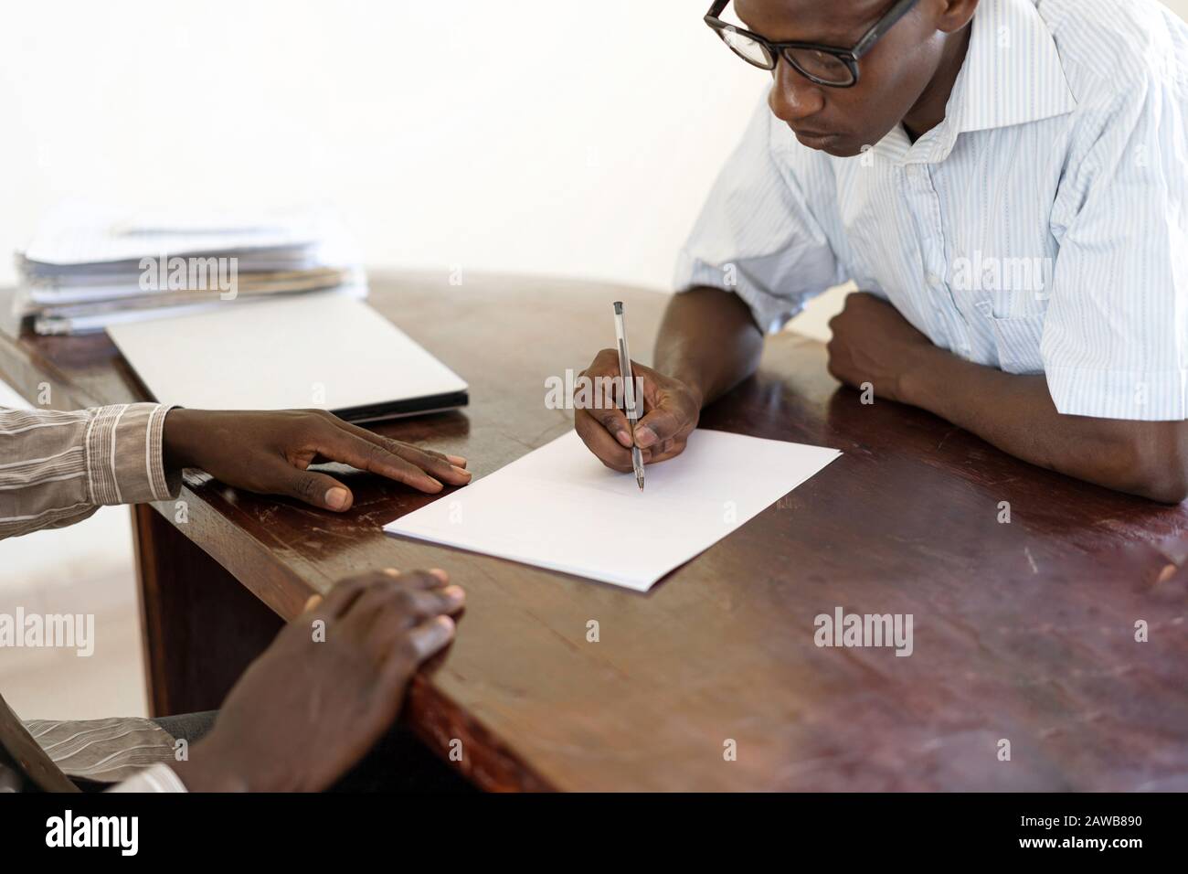 Erster Arbeitstag für diesen jungen afrikanischen Entrepeneur, der seinen Vertrag auf dem Schreibtisch im Büro des Chefs unterzeichnet Stockfoto