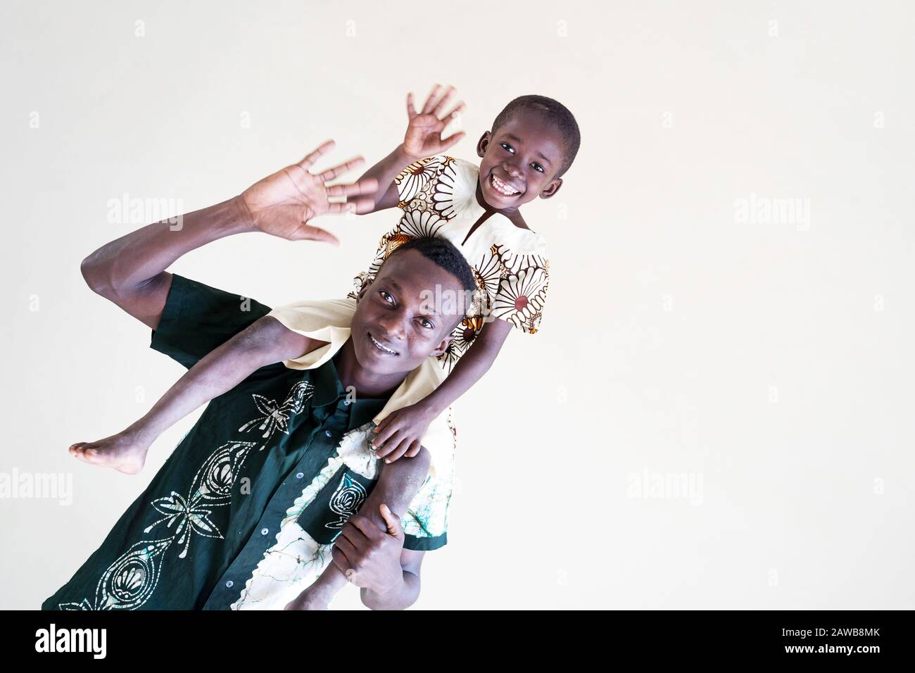 Der schiefe Schuss von afrikanischem schwarzen Vater und Sohn, der vor einem isolierten Hintergrund lächelnd Spaß hatte und zusammen als Symbol für Vielfalt lachte Stockfoto