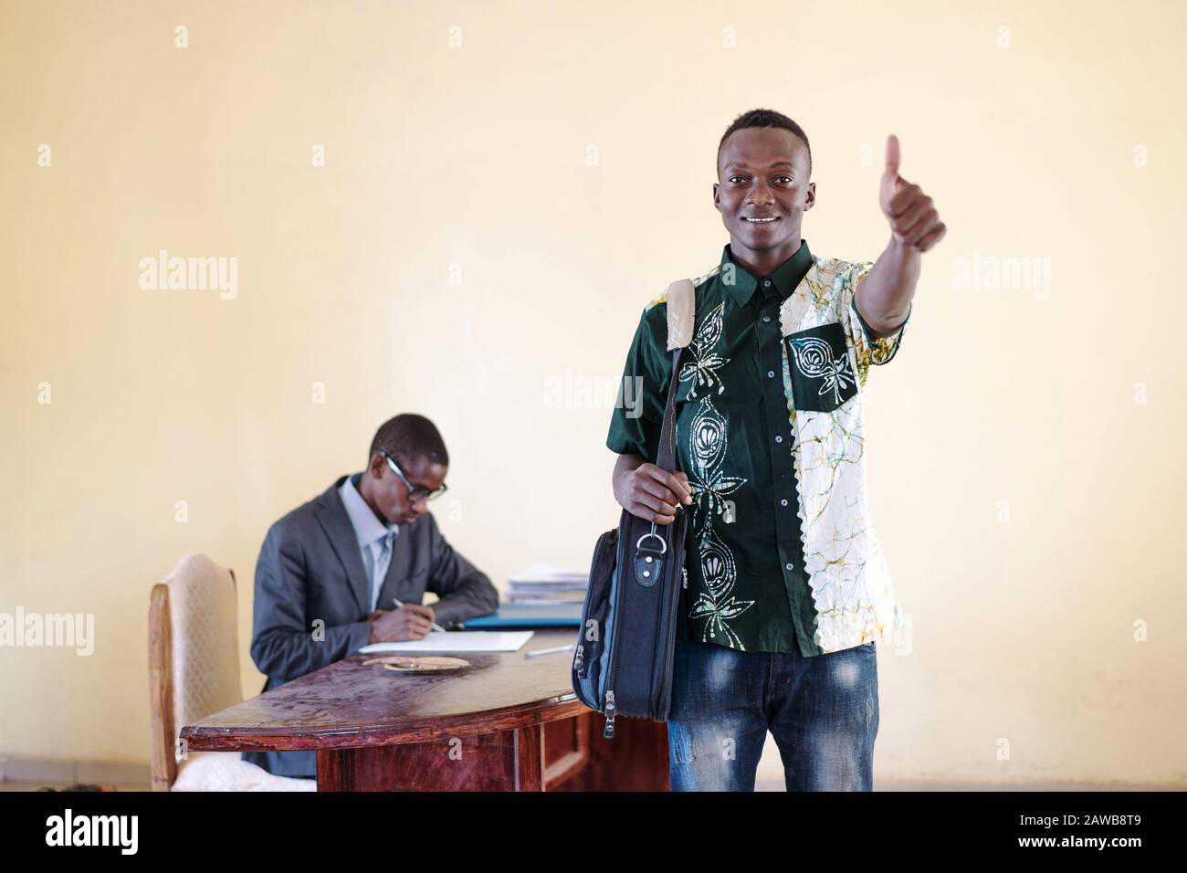 Junger und fröhlicher afrikanischer Business-Mitarbeiter, der seinen Daumen zeigt, um Glück und fröhliches Lächeln zu zeigen, das isoliert im Hintergrund zu sehen ist Stockfoto