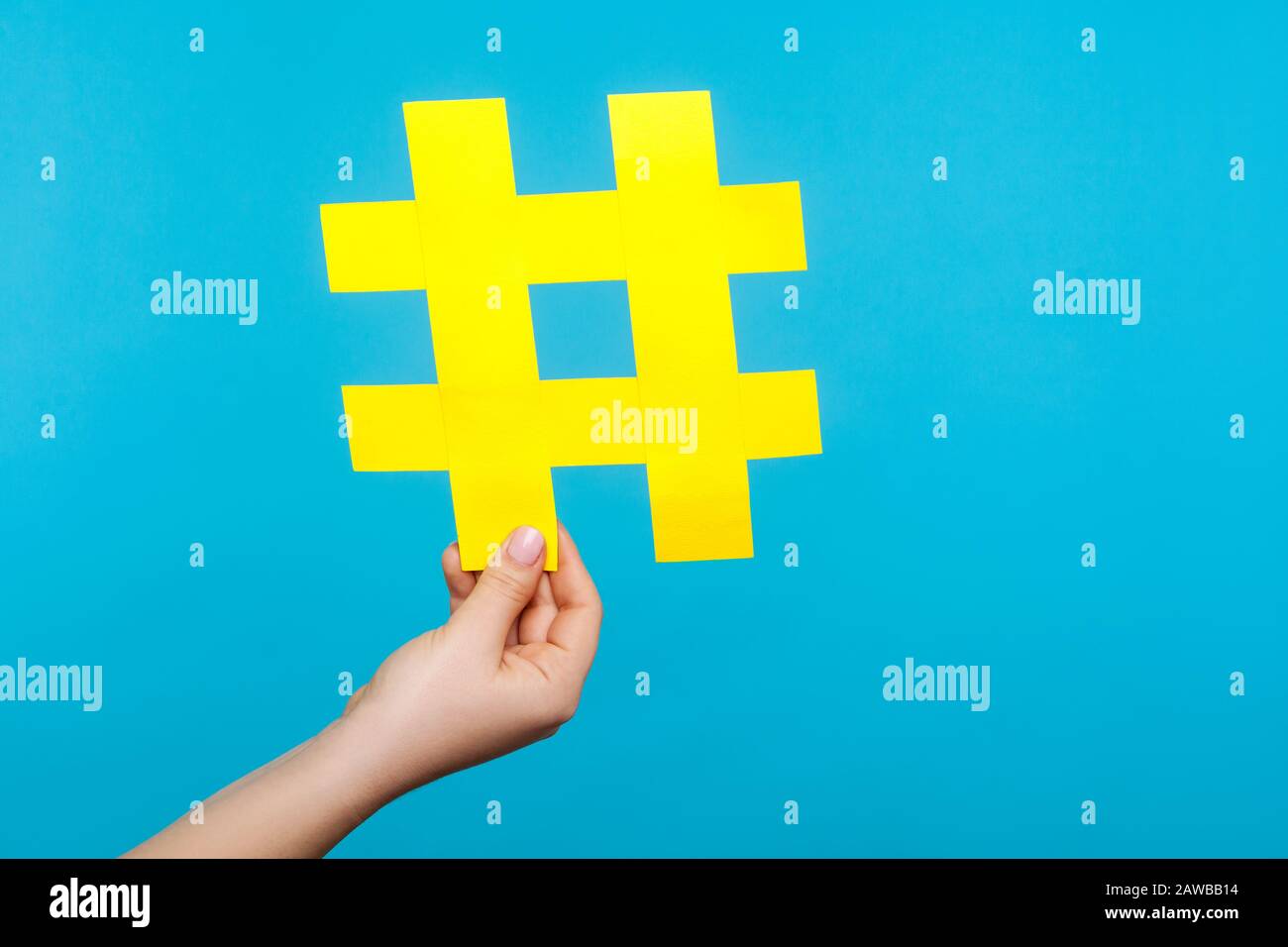 Nahaufnahme der weiblichen Hand, die großes gelbes Papierhashtag-Zeichen, Hash-Symbol für Internetbeliebtheit, berühmte Medientrends, Blogging und virale Inhalte hält. IND Stockfoto
