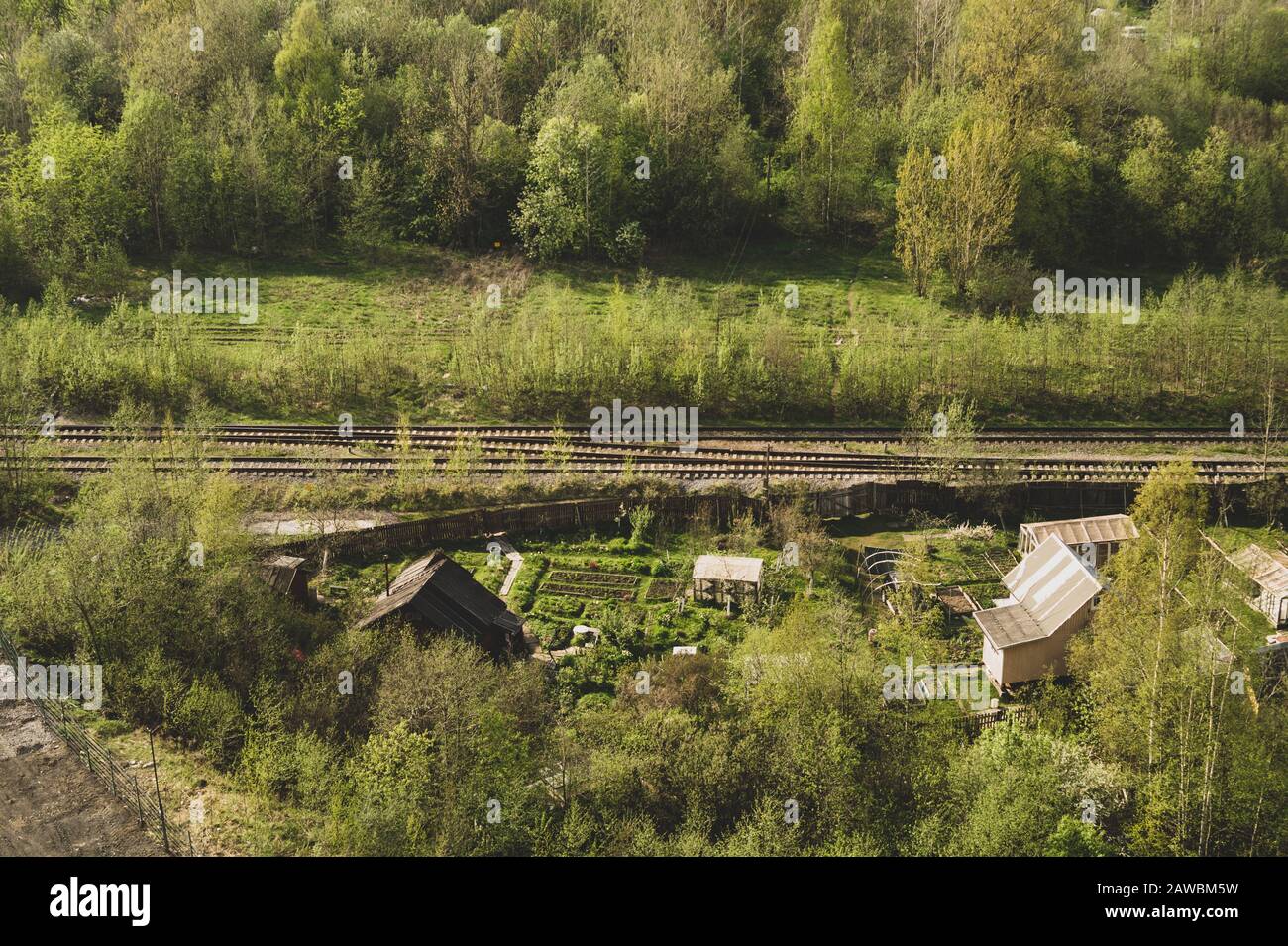 Haus mit Garten in der Nähe von Bahnlinien. Holzhaus im Wald Luftbild. Ländliche Landschaft aus der Höhe Stockfoto
