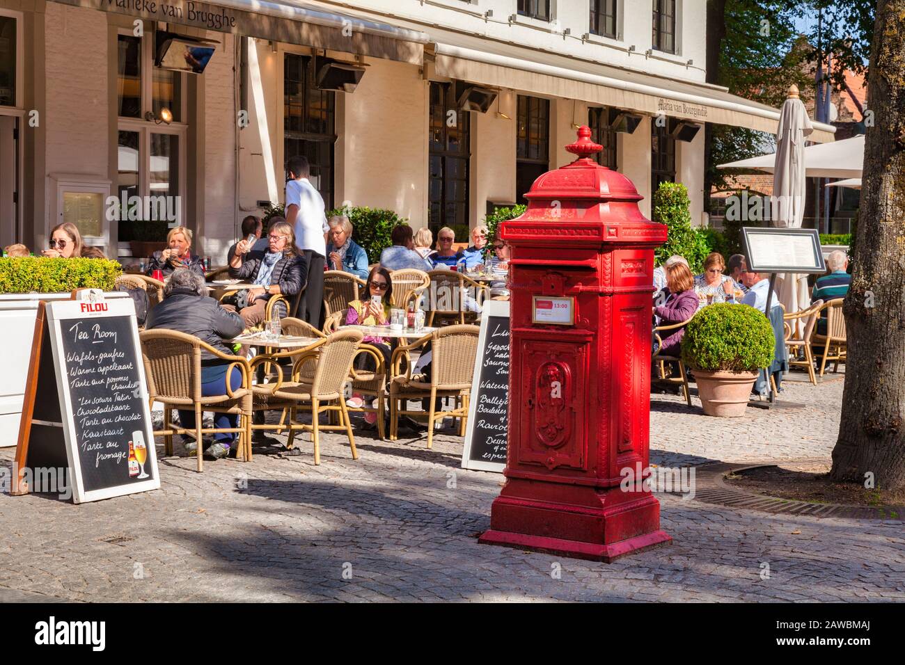 25. September 2018: Brüggen, Belgien - Kunden, die vor einem Teestube sitzen, und ein Briefkasten im historischen Herzen der Altstadt. Stockfoto