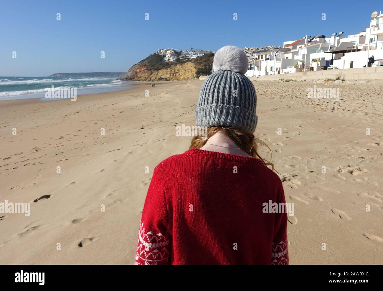 Mädchen im Winter am Strand in Portugal in einer Kopfmütze Stockfoto
