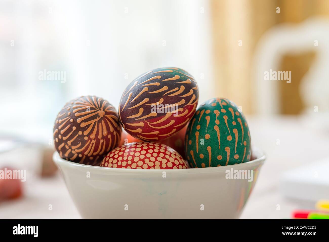 Buntes Wachs malte Ostereier in Schüssel auf Holztisch, mit Wachs bemalte Verzierungen, Regenbogenblumen, Punkte Stockfoto