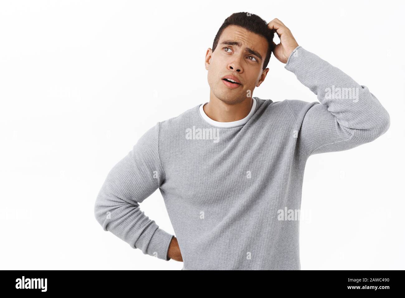 Nachdenklicher und zögerlicher, gut aussehender junger Mann, das Nachsehen fokussiert, den Kopf nachdenklich, sich an etwas wichtiges erinnern, unsicher stehen Stockfoto