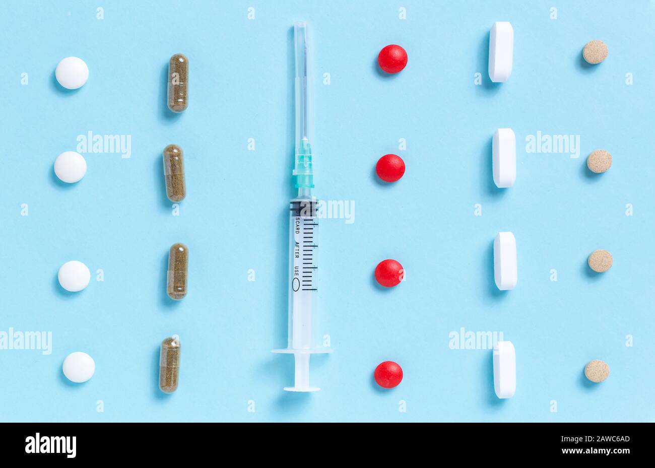 Medizinische Spritze mit Reihen verschiedenfarbiger Pillen Stockfoto