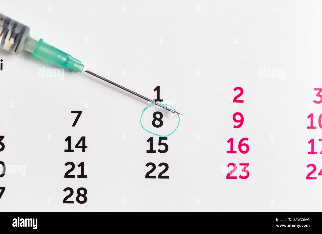 Spritze mit Impfstoff fällt über einen Kalender. Denken Sie daran, Ihren Impfstoff, Ihre Injektion und Ihr Fruchtbarkeitskonzept zu erhalten Stockfoto
