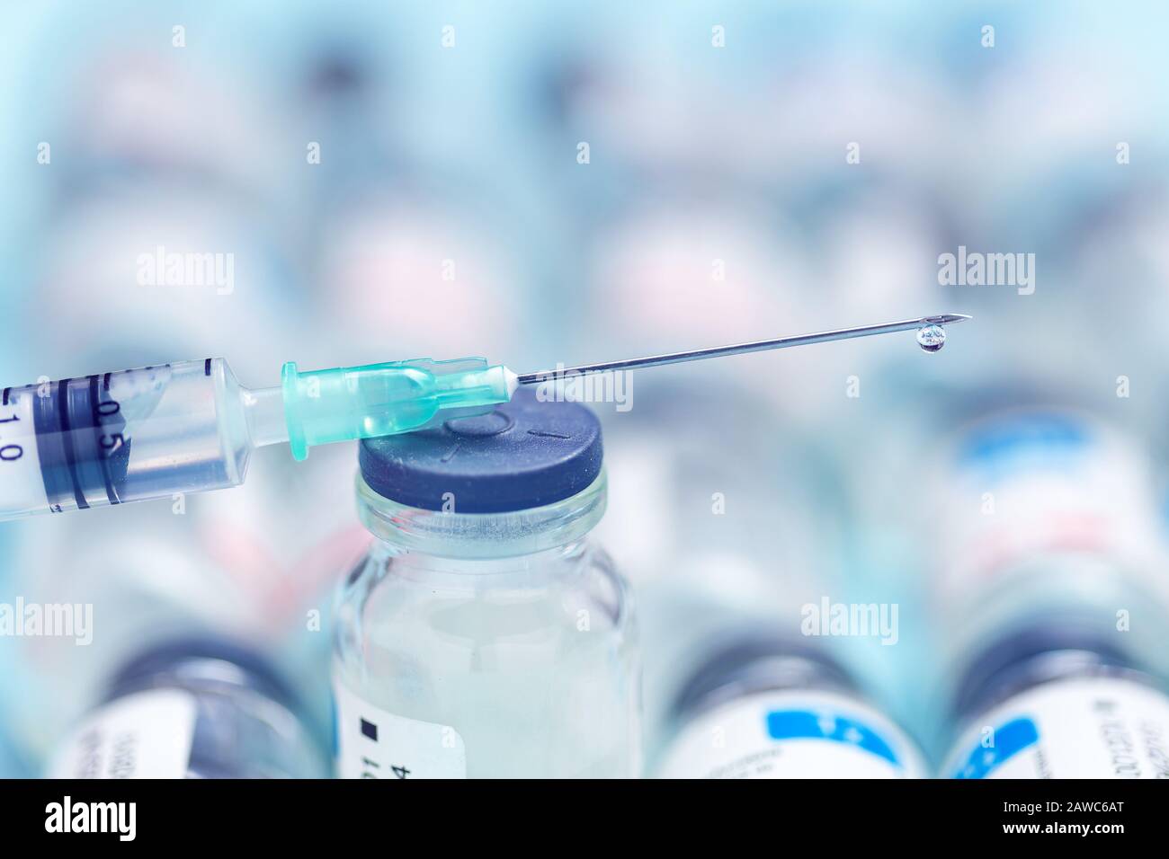 Spritze über Arzneiflaschen auf blauem Hintergrund. Injektionsnadel und Medikamente für den medizinischen Hintergrund. Impfkonzept. Stockfoto