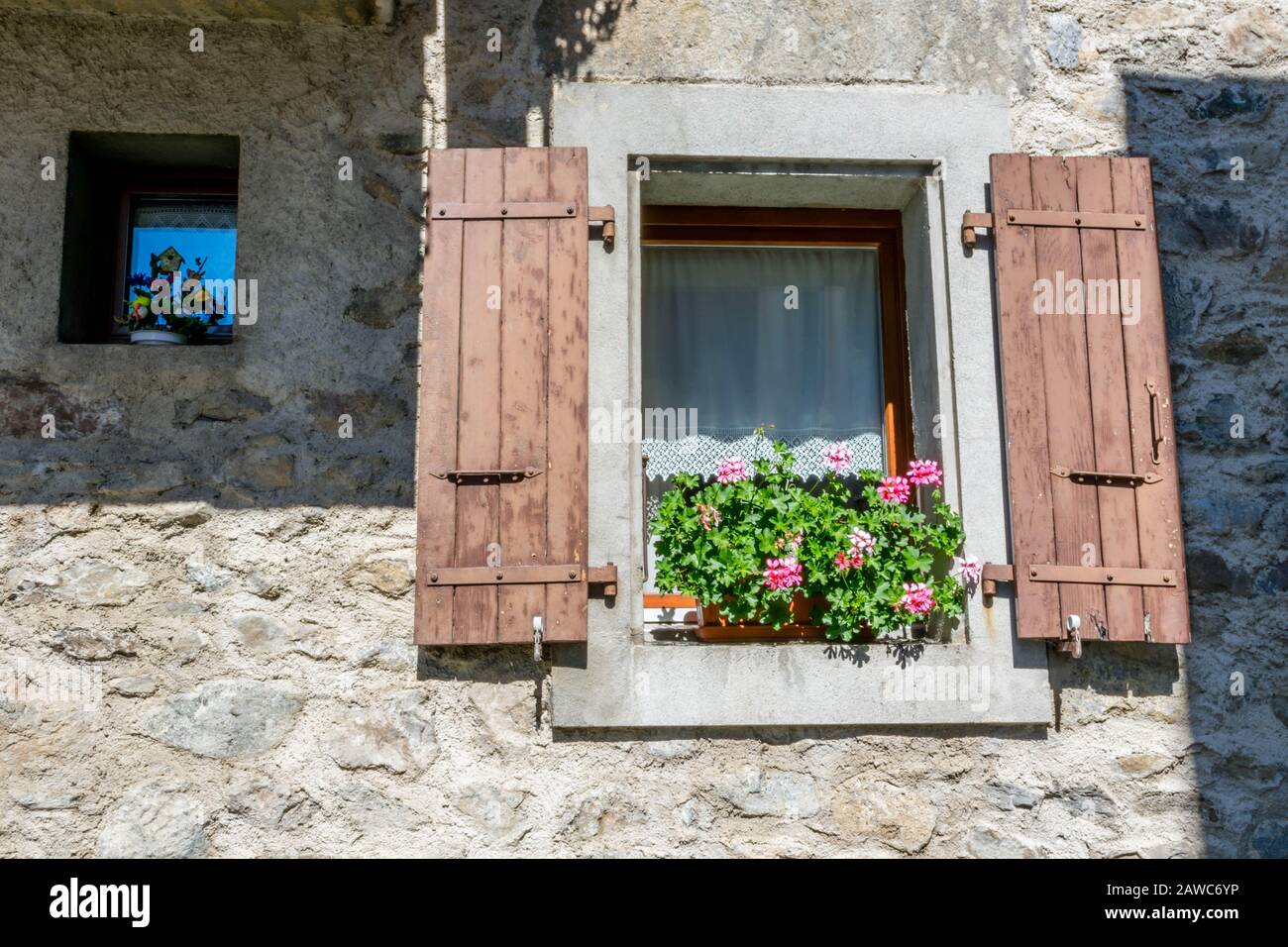 Kleine und große Fenster an der Steinmauer Stockfoto