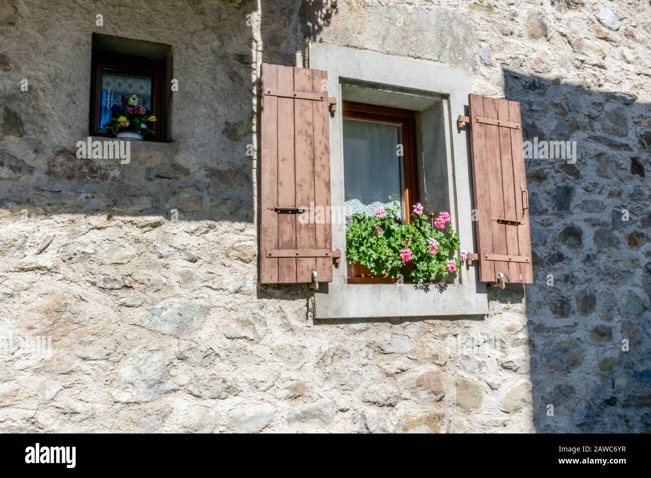 Kleine und große Fenster an der Steinmauer Stockfoto
