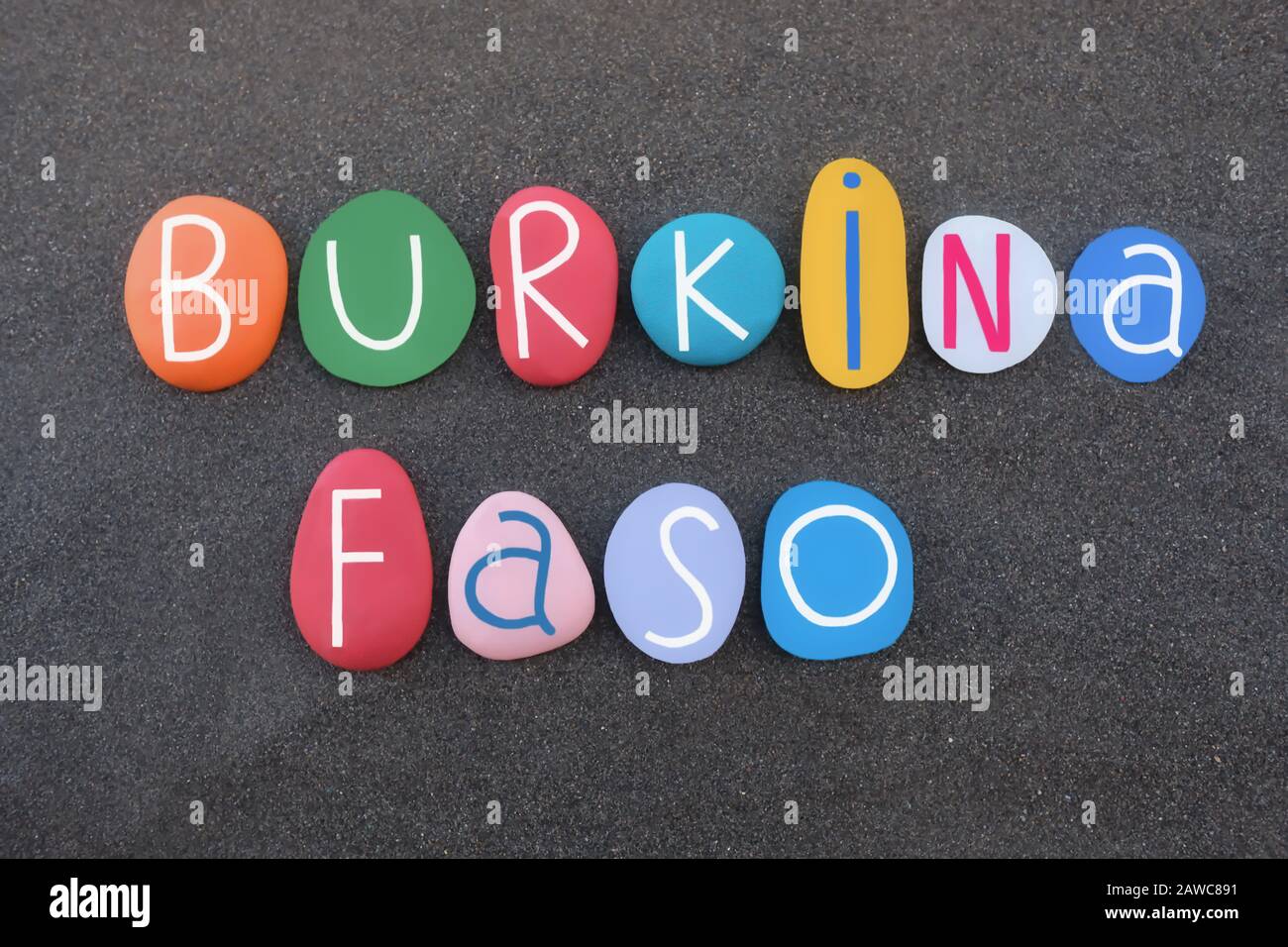 Burkina Faso, Republik Burkina Faso, Souvenir mit farbigen Steinbuchstaben über schwarzem Vulkansand Stockfoto