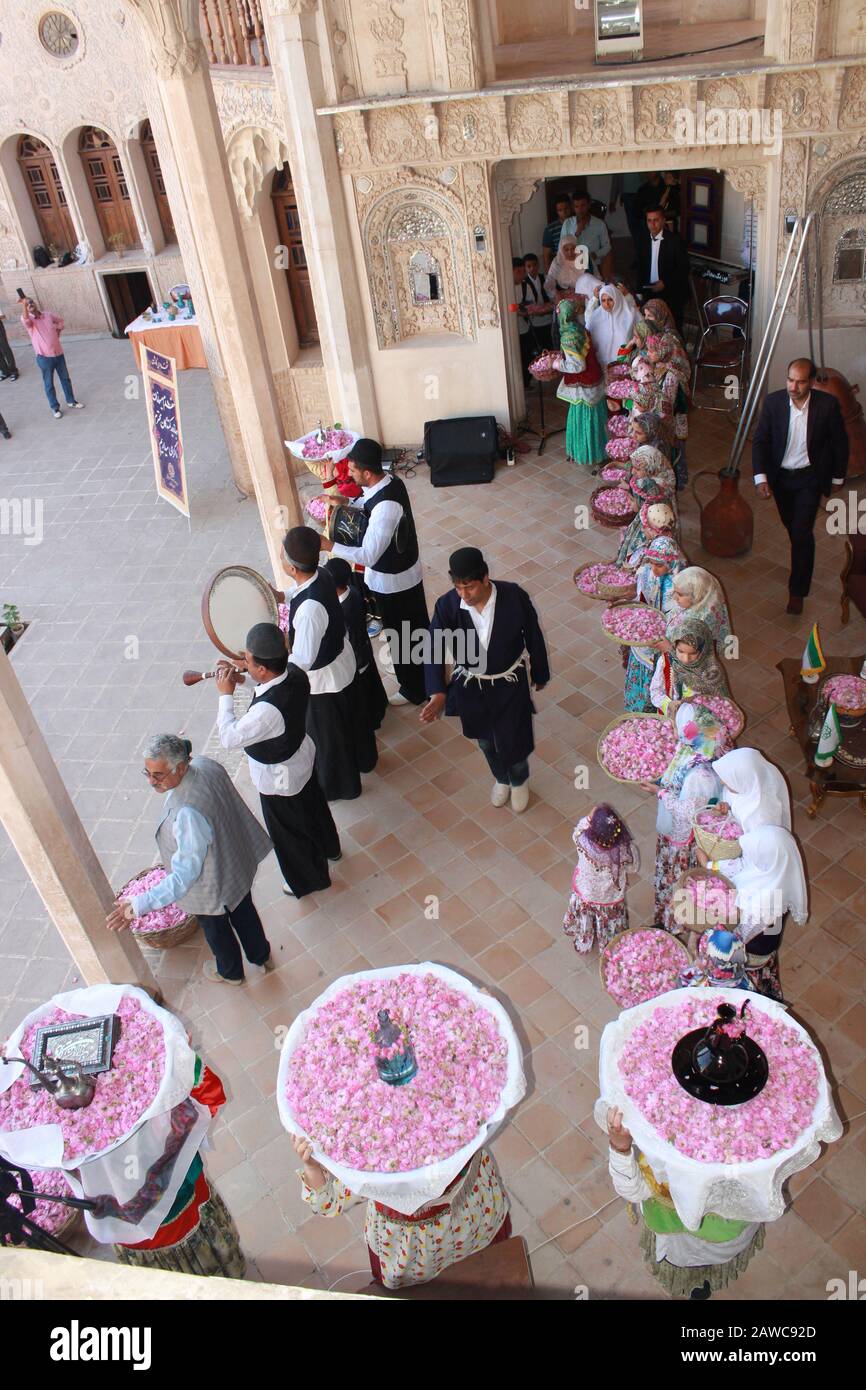 Iranische Männer und Frauen in lokalen Kostümen beim Rosenfest in Kashan, tragen Körbe mit Rosen und Rosenwasser über den Kopf und spielen Musik Stockfoto
