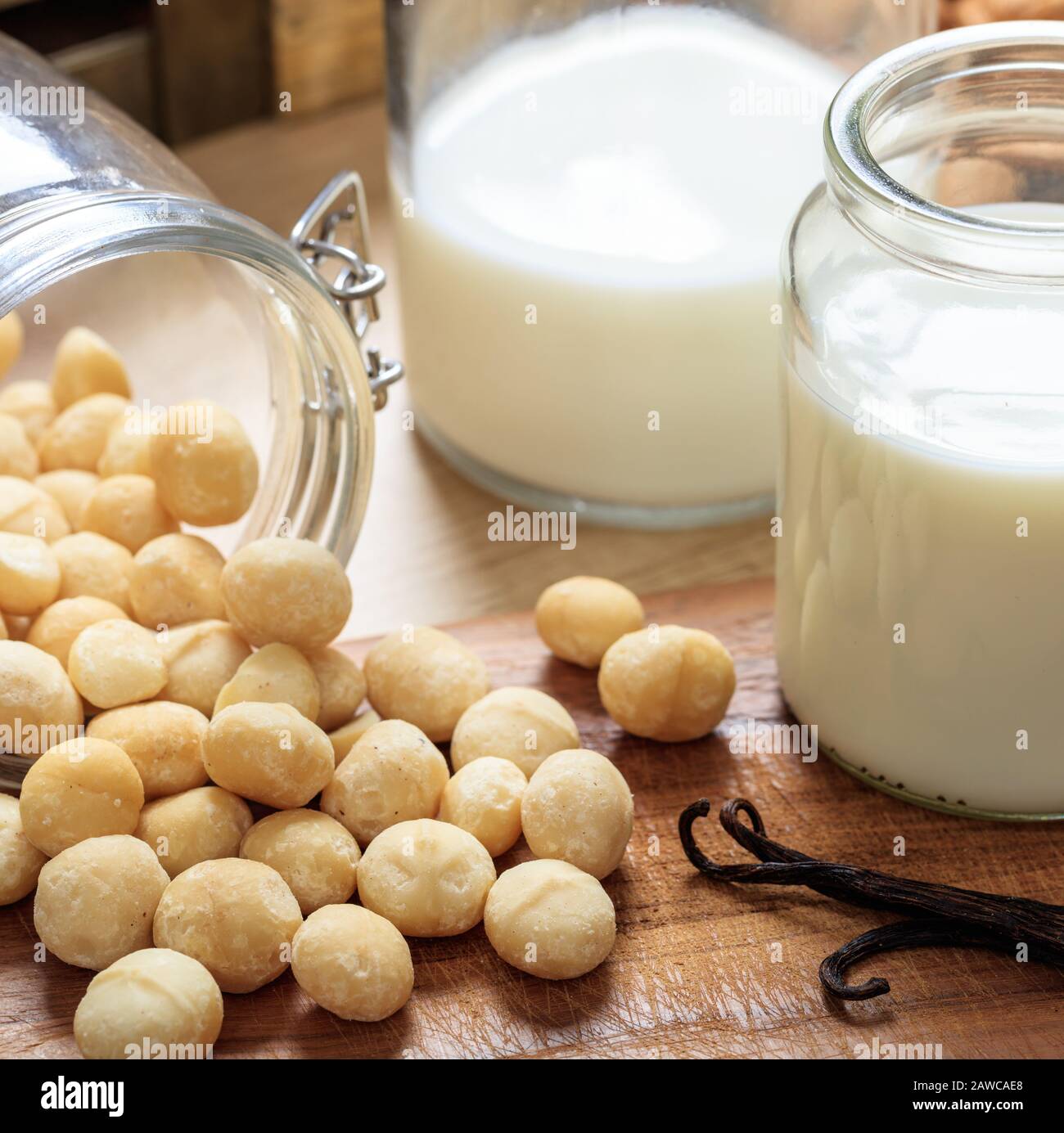Macadamia-Milch, keine Milch, Ersatzmilch auf einem Holztisch. Nüsse und Glas mit Milch, laktosefreier Milchersatz für Veganer Stockfoto