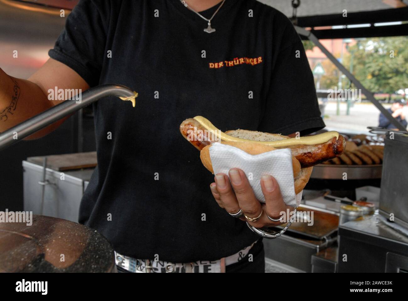 Eine deutsche Wurst wird an einem der ursprünglichen Thüringer Wurststände am Alexanderplatz im Zentrum von Berlin mit Senf bestochen. Die Stockfoto