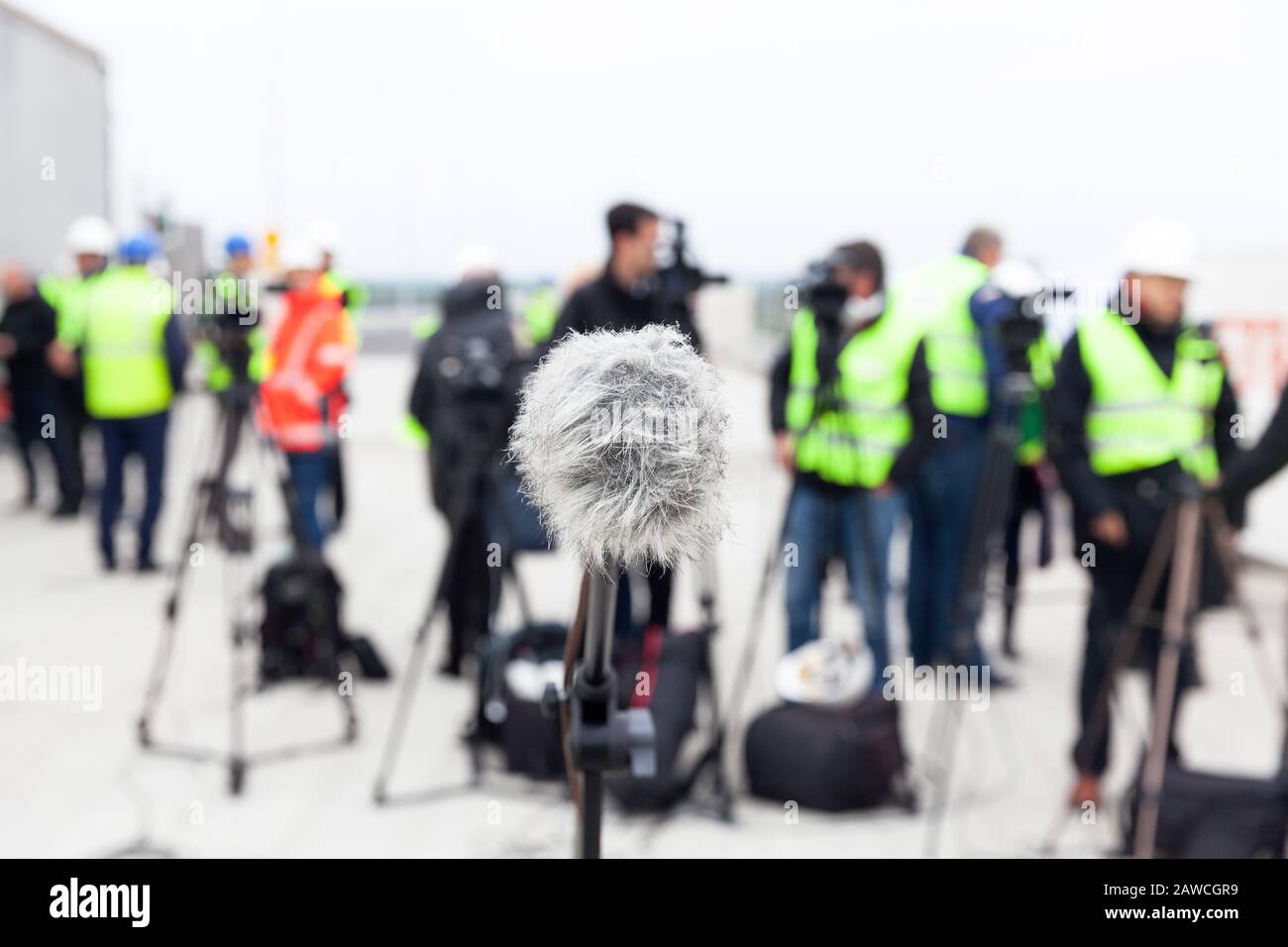 Mikrofon im Fokus gegen verwackelte Kamera Operatoren und Reporter an der Pressekonferenz Stockfoto