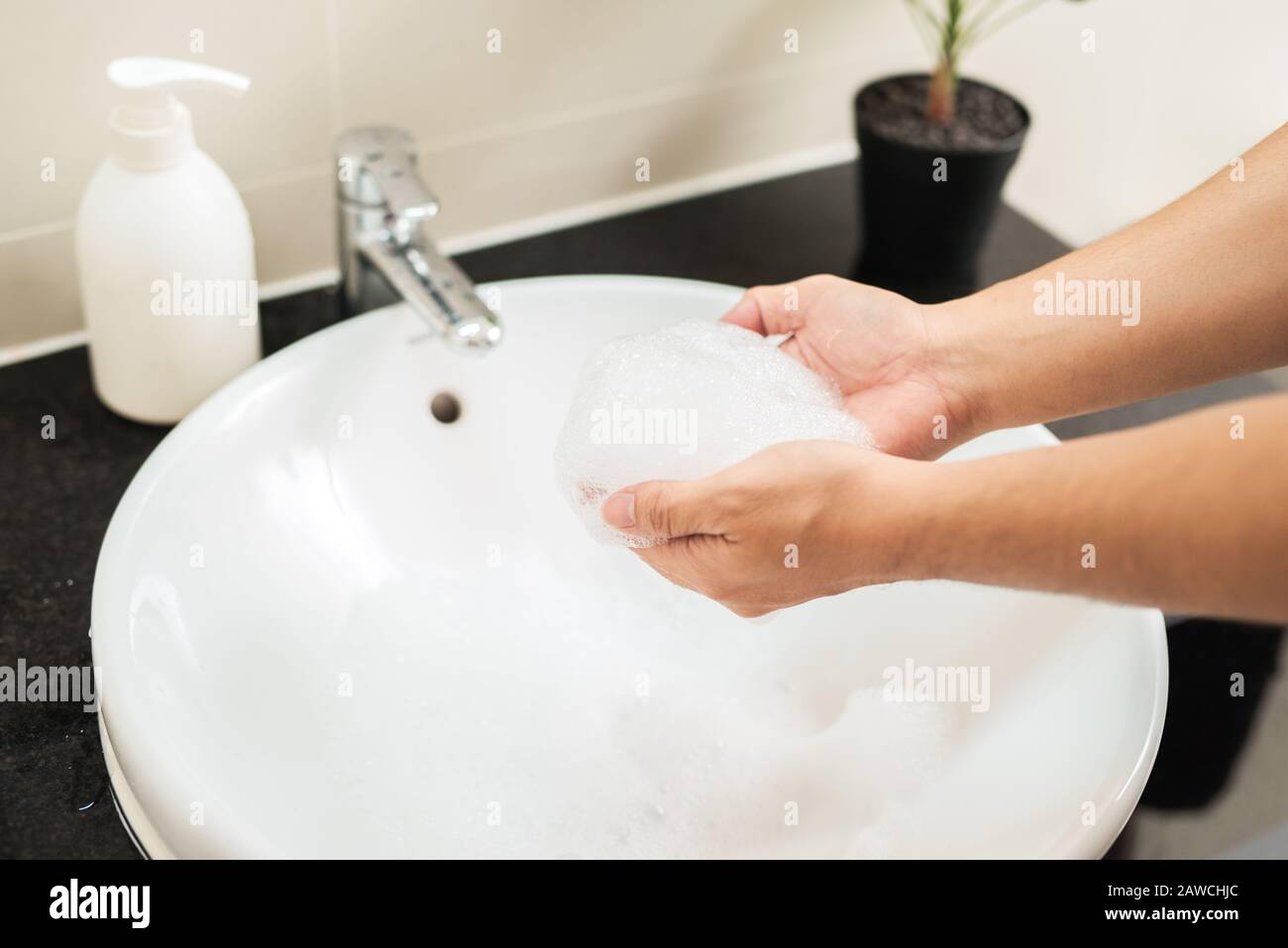 Hygienekonzept. Der Mann wäscht seine Hände im Badezimmer mit Seife unter fließendem Wasser. Stockfoto