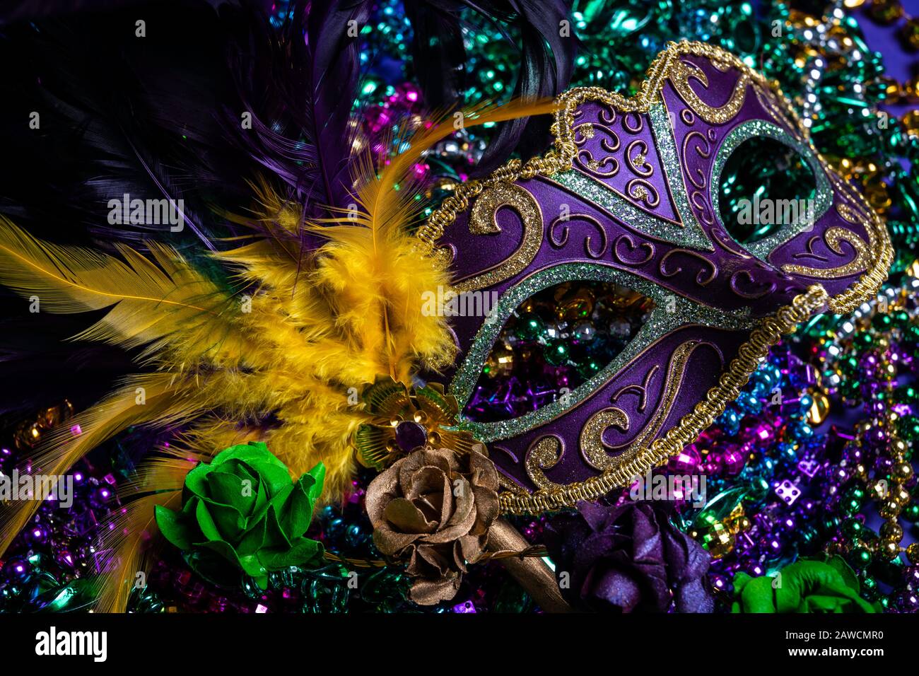 Bunte Mardi Gras Maske auf violettem Hintergrund mit Perlen Stockfoto