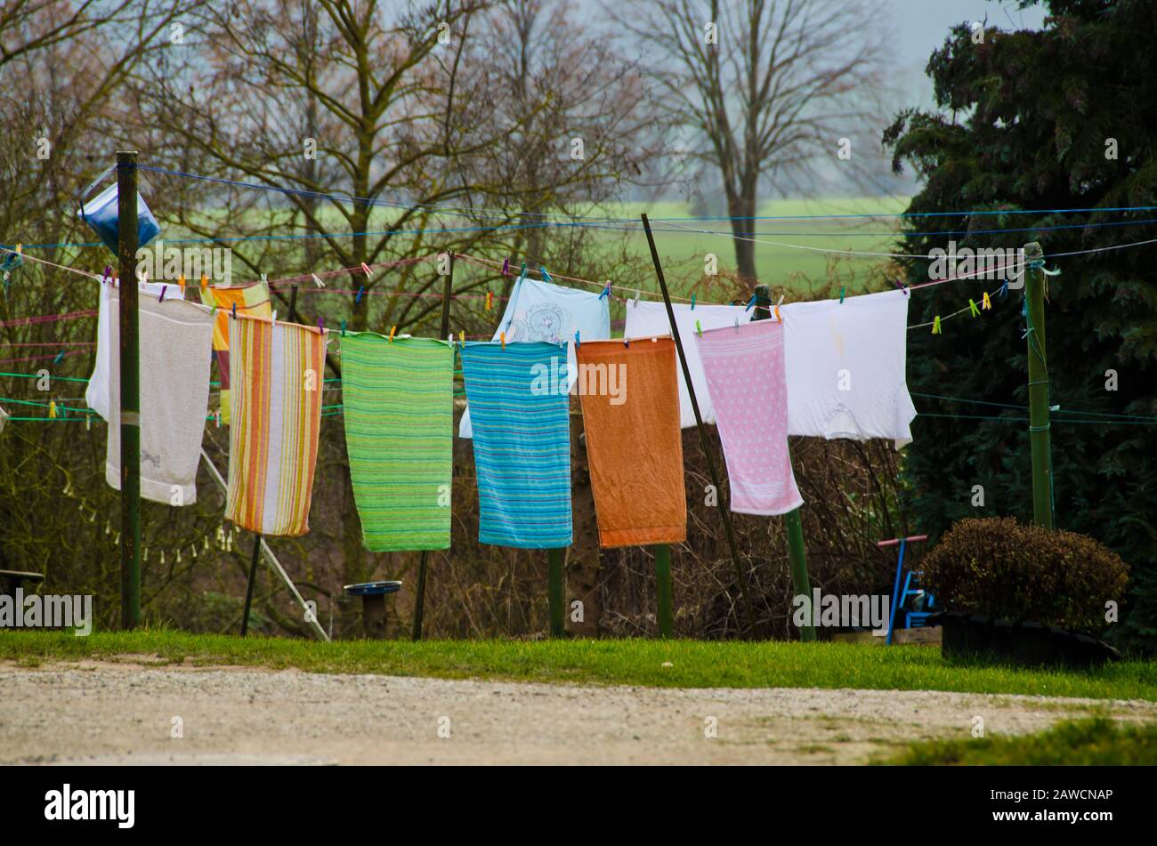 Viele bunte Handtücher und Waschsalon hängen an einer Kleidungslinie in einem Innenhof eines alten Bauernhauses Stockfoto