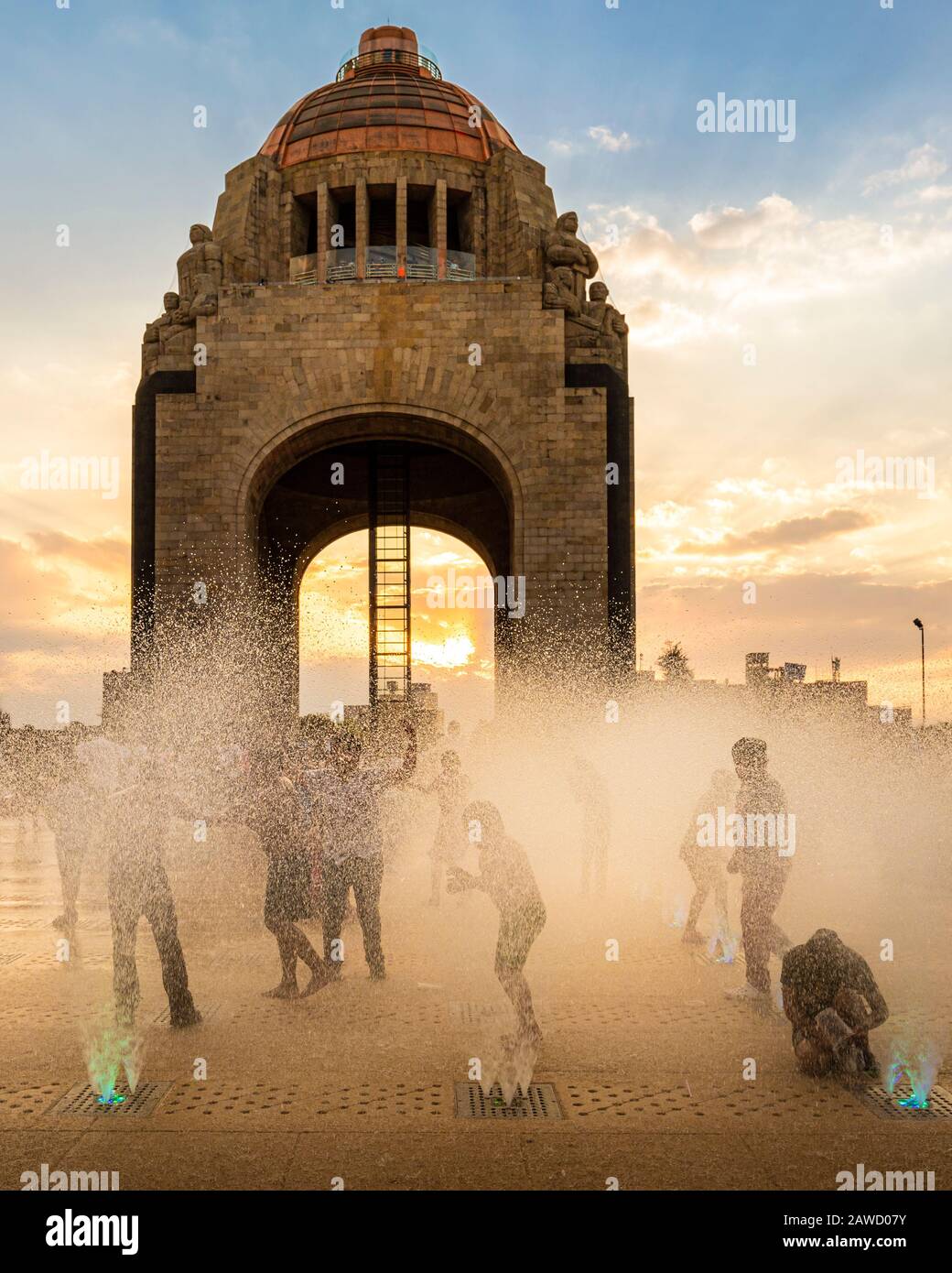 Kinder spielen in den Brunnen der Monumenta a la Revolucion bei Sonnenuntergang in Mexiko-Stadt, Mexiko. Stockfoto