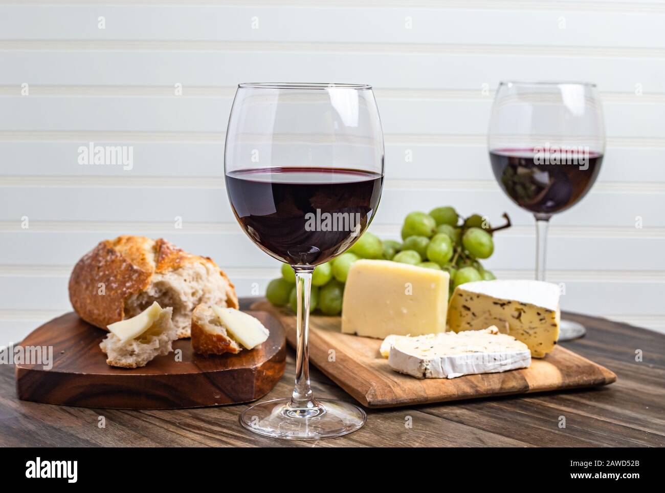 Wein- und Käseplatte serviert mit Trauben auf Holzoberfläche mit weißem Hintergrund Stockfoto