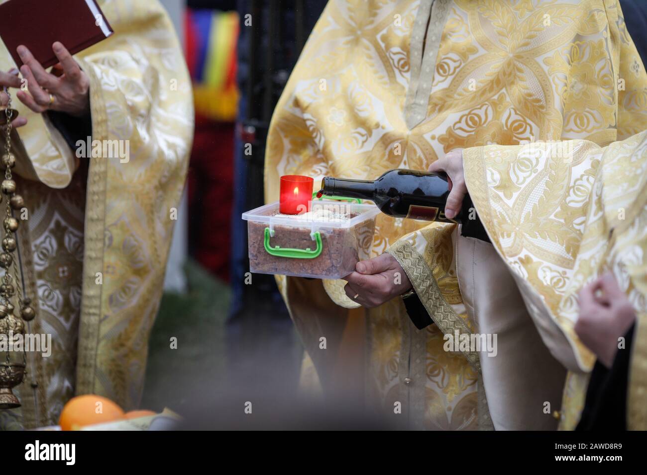 Flache Schärfentiefe (selektiver Fokus) Bild mit einem orthodoxen Priester, der während einer Zeremonie Wein auf einen Trauerkuchen gießt. Stockfoto