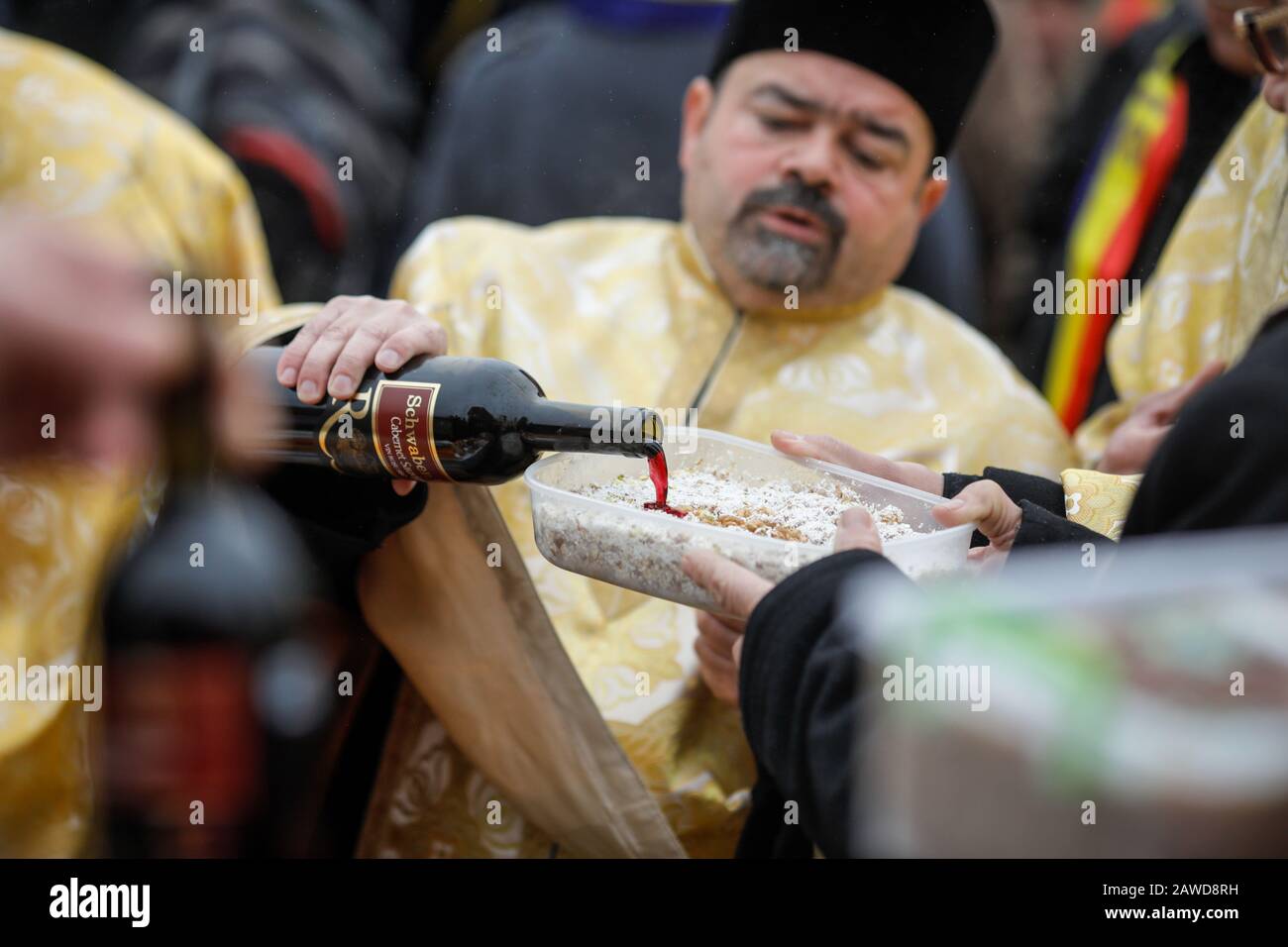 Popesti Leordeni, Rumänien - 20. Dezember 2019: Flache Schärfentiefe (selektiver Fokus) Bild mit einem orthodoxen Priester, der Wein auf einen Beerdigungskuchen gießt d Stockfoto