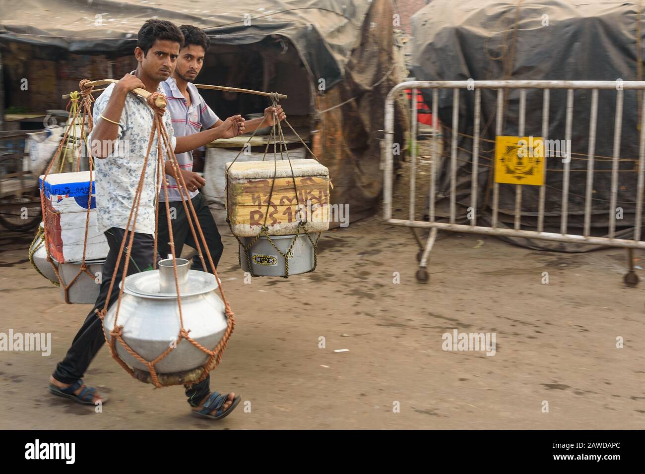 Indische Männer tragen Lebensmittel und Getränke in Töpfen auf Joch entlang der Straße. Kolkata. Indien Stockfoto