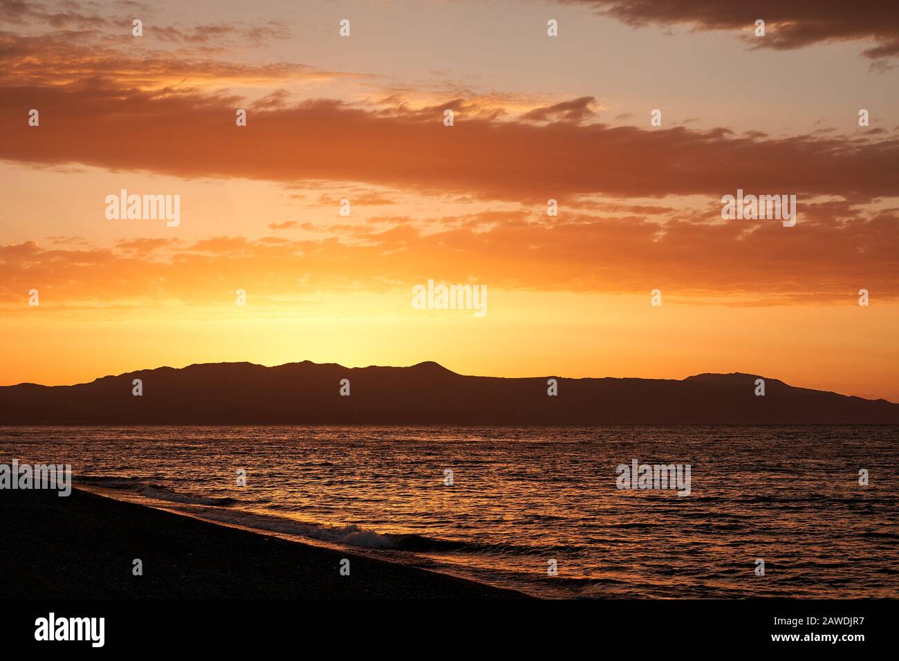 Sonnenuntergang auf der griechischen Insel - Farben bei Sonnenuntergang am Hafen von Malia Hersonissos in der Nähe von Heraklion, Crete, Griechenland mit den Bergen, die das Meer in Silhuette berühren Stockfoto