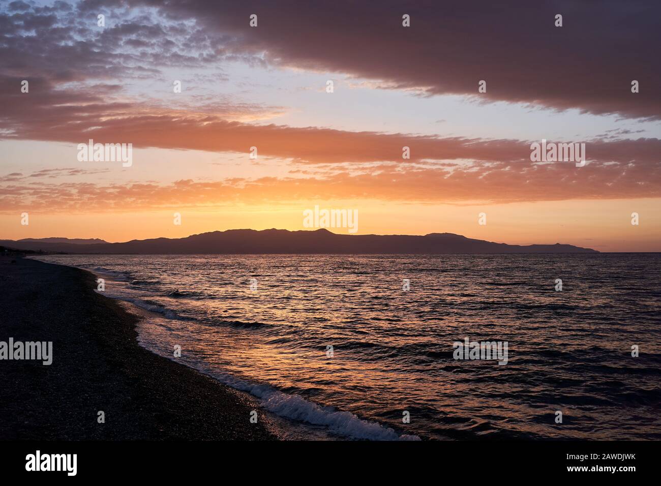 Sonnenuntergang auf der griechischen Insel - Farben bei Sonnenuntergang am Hafen von Malia Hersonissos in der Nähe von Heraklion, Crete, Griechenland mit den Bergen, die das Meer in Silhuette berühren Stockfoto