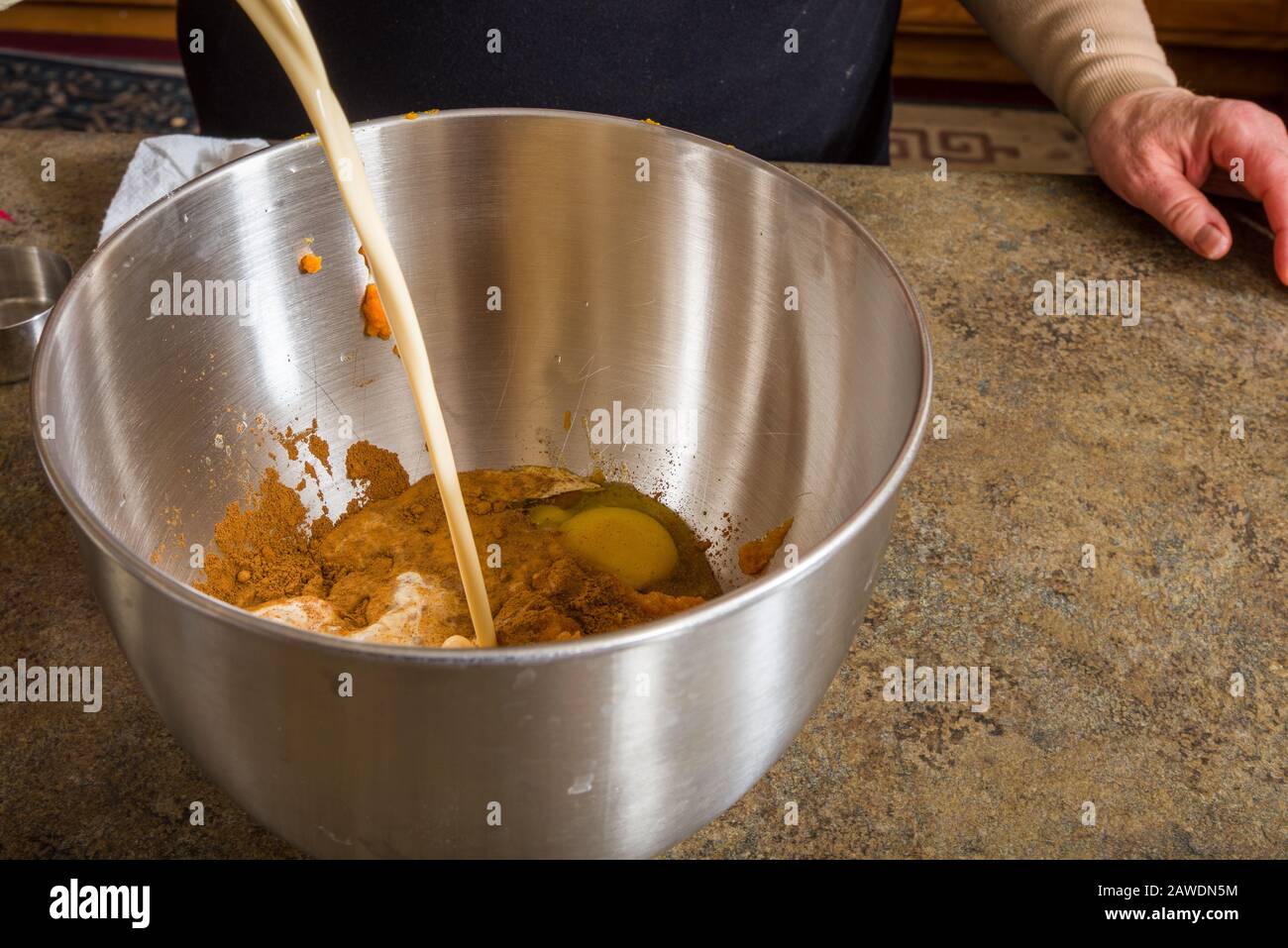 Eine Kürbiskuchen, die in einer Schüssel gemischt wird und Creme hinzugefügt wird Stockfoto