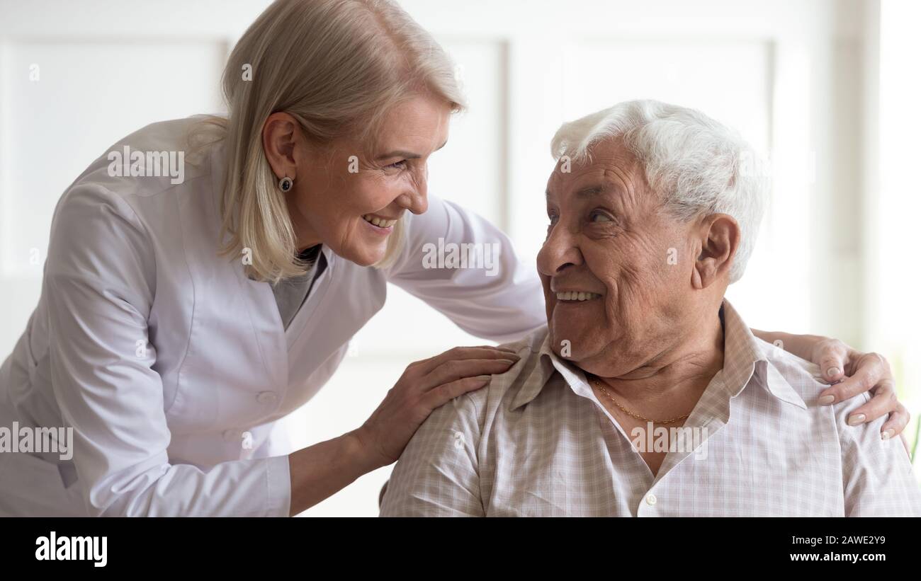 Positive weibliche Krankenschwester, die sich um eine ältere männliche Patientin kümmert Stockfoto