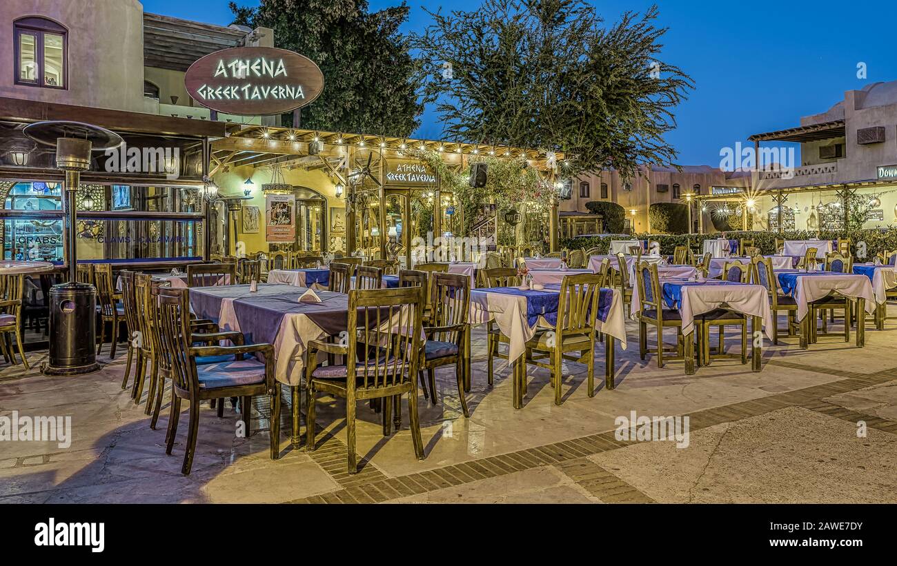 Griechische Taverne mit Tischen und Stühlen auf einem kleinen Platz in der Abenddämmerung bei Sonnenuntergang in der Innenstadt von el Gouna, Ägypten, 16. Januar 2020 Stockfoto