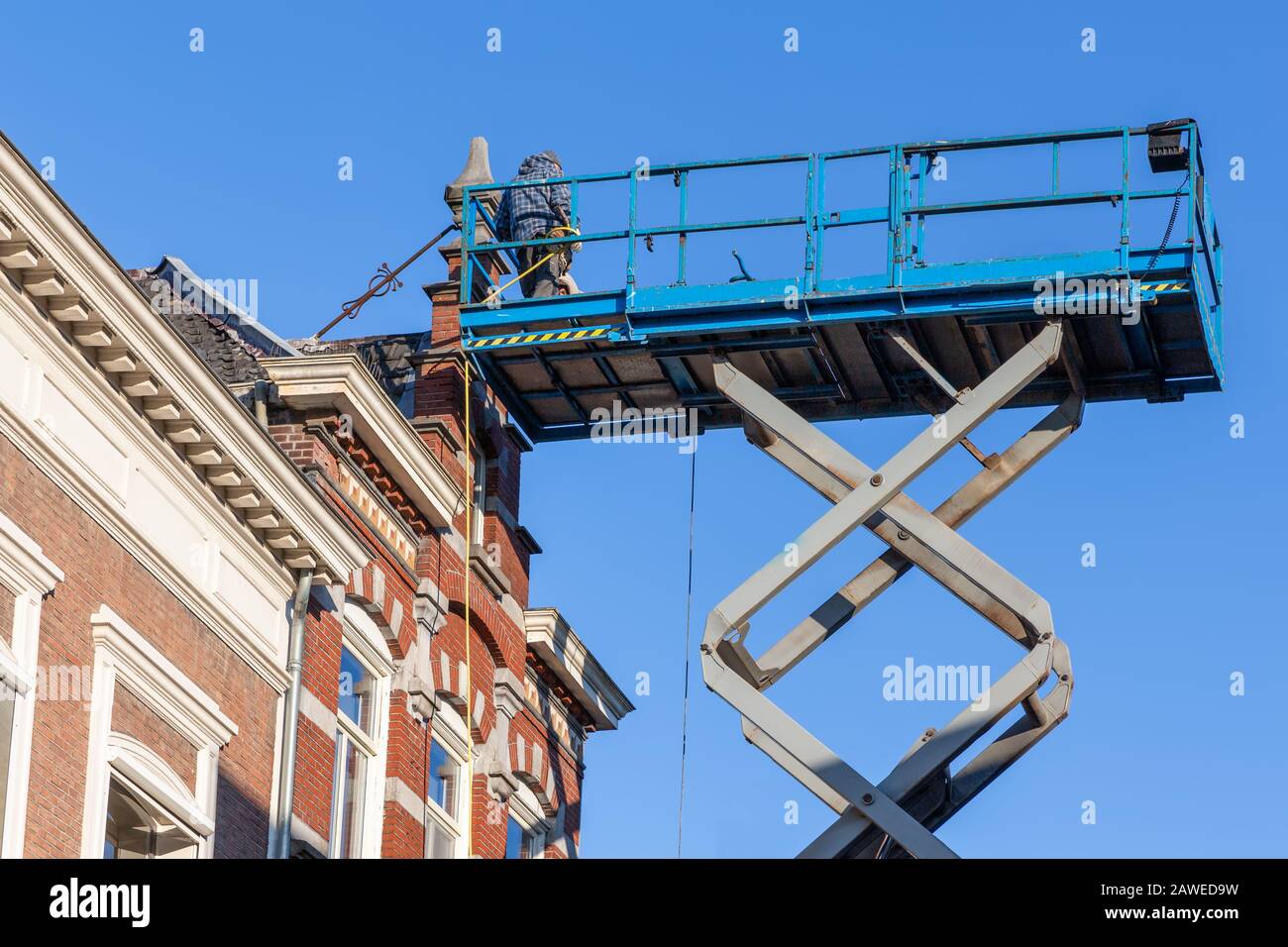 Arbeitsplattform mit Baumeistern, die das historische holländische Haus reparieren Stockfoto