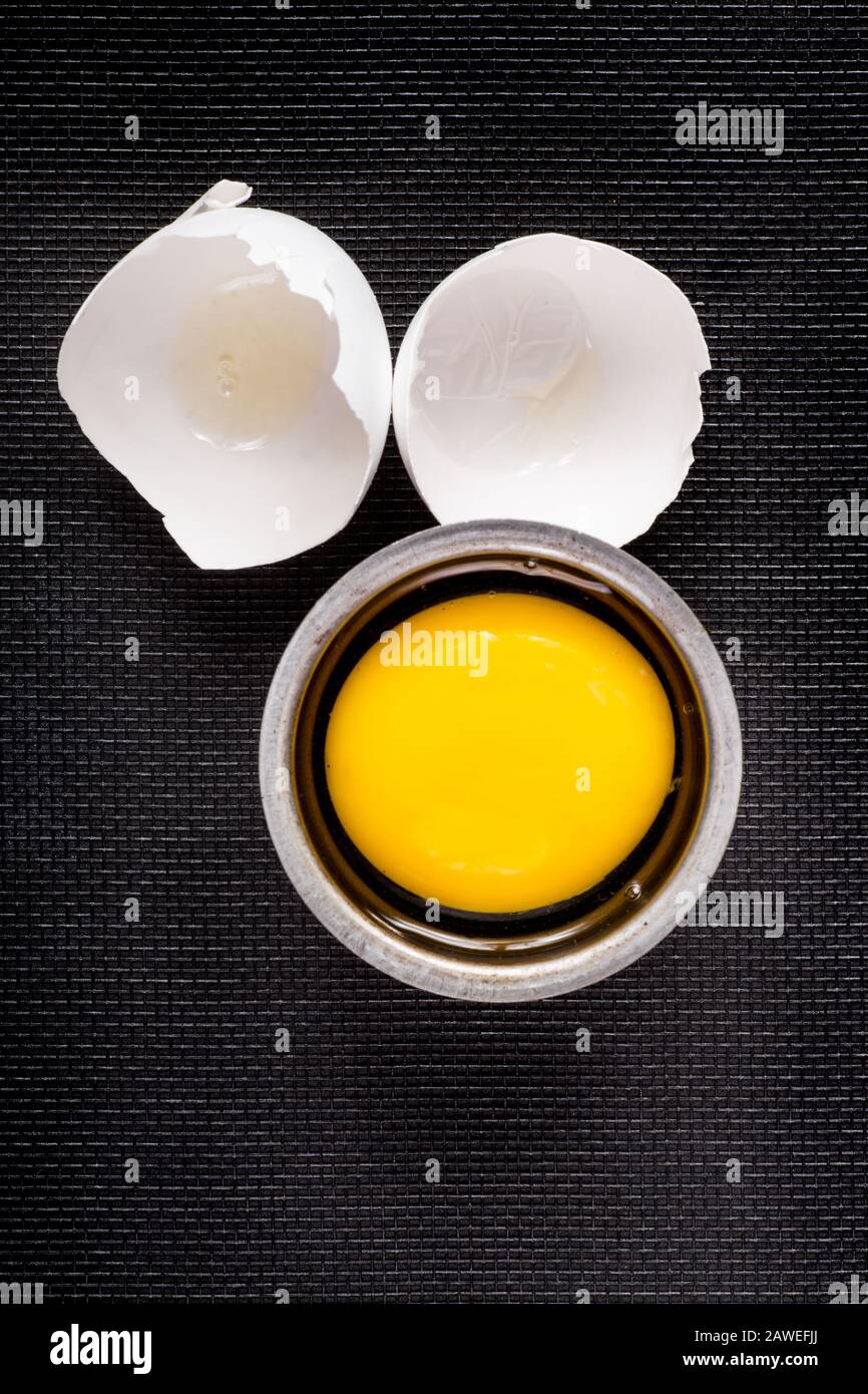 Ei auf Schwarz mit gerissenen Schalen und Eigelb Stockfoto