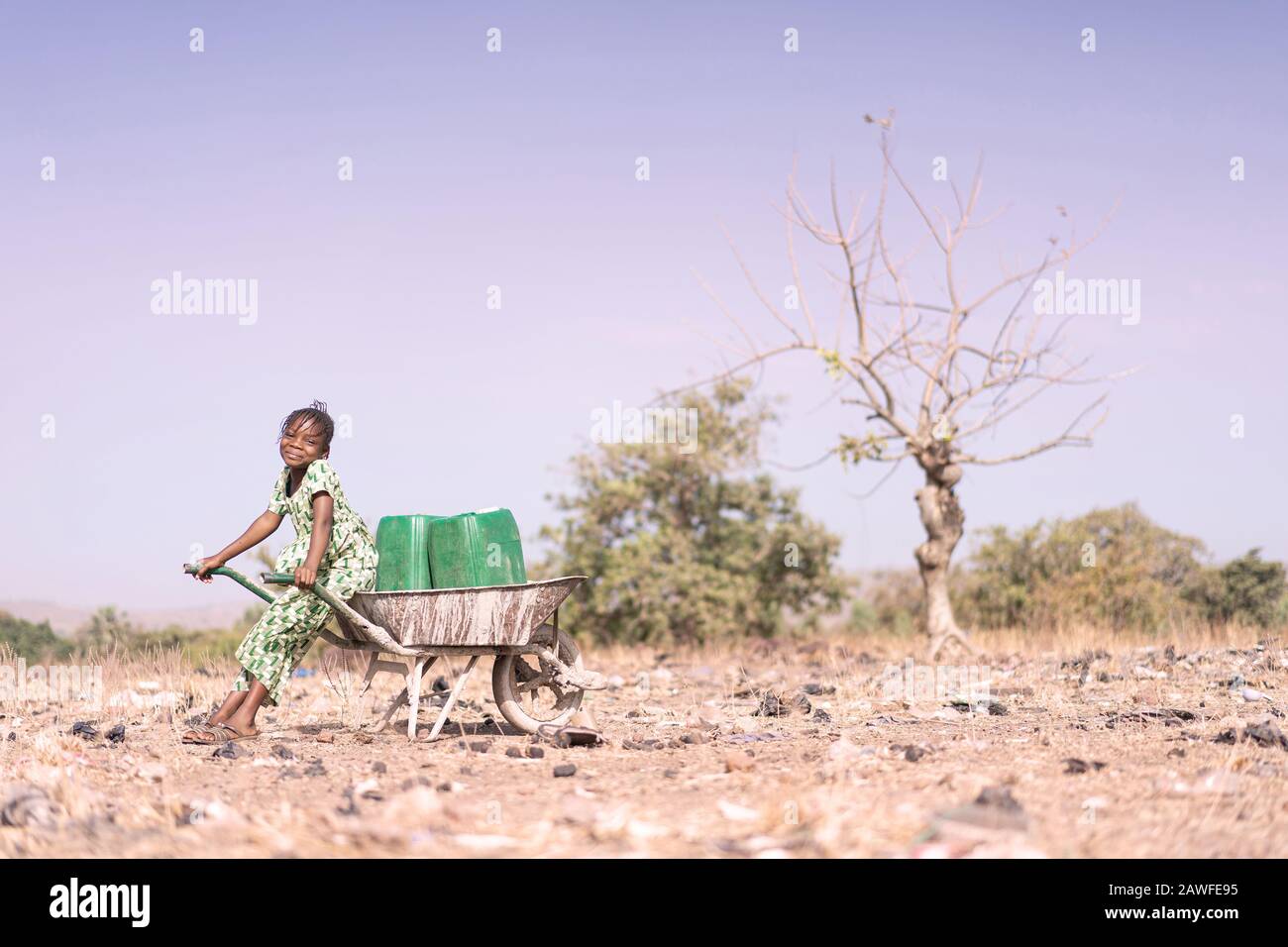 Winziger westafrikanischer Youngster, Der viel Wasser für ein Dehydrationskonzept Sammelt Stockfoto
