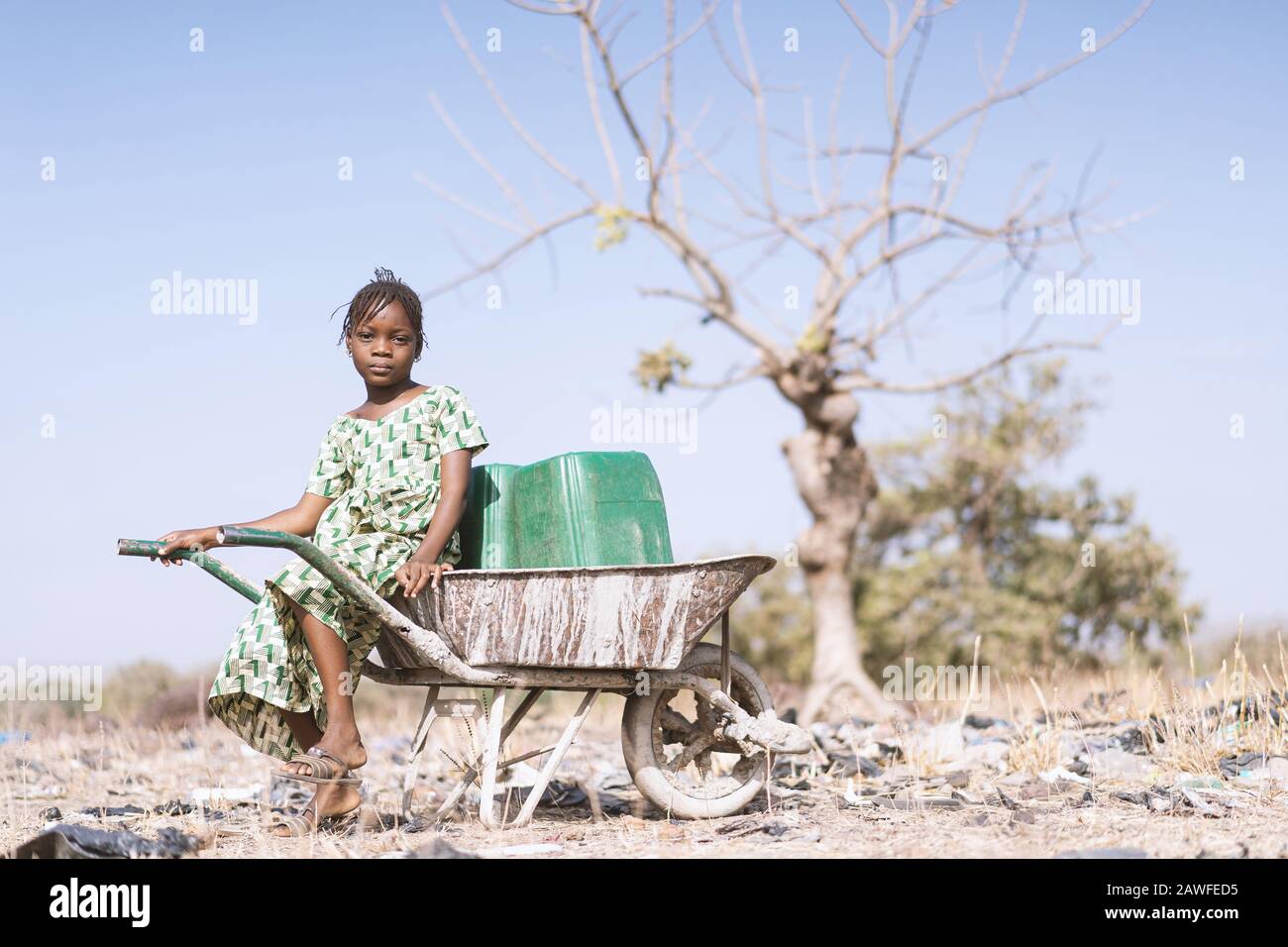 Fröhliches westafrikanisches Schulmädchen Arbeitet mit Sauberem Wasser für ein Symbol für Wassermangel Stockfoto