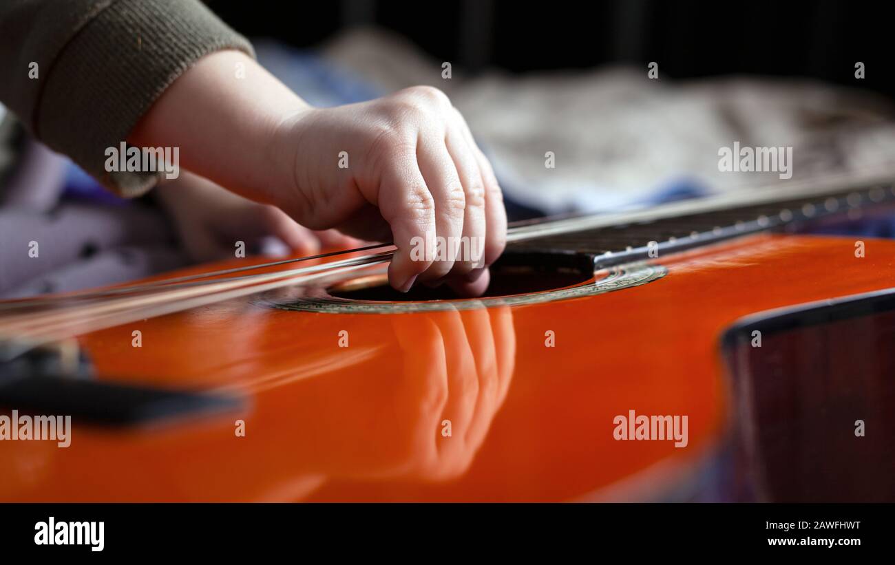 Kleines Mädchen versucht, die Saiten an der Gitarre zu reißen. Stockfoto