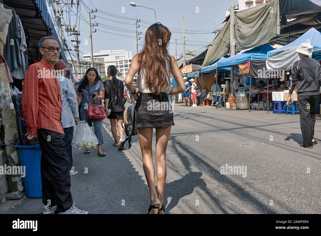 Frau trägt einen Minirock zieht einen flüchtigen Blick von männlichen Bewunderer; Thailand Straße Stockfoto