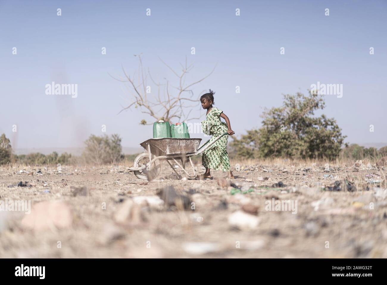 Arme westafrikanische Kleinkinder Arbeiten mit nährstoffreichem Wasser in einer natürlichen Umgebung Stockfoto