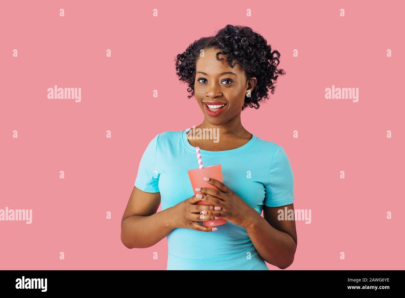 Nahaufnahme des Porträts einer jungen lächelnden Frau, die ein Getränk mit Strohhalm hält und die Kamera betrachtet Stockfoto