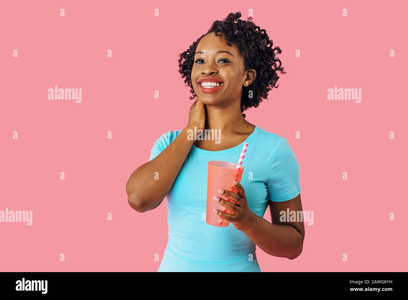 Nahaufnahme des Porträts einer jungen lächelnden Frau, die einen Drink mit Strohhalm hält und mit der Kamera schaut Stockfoto