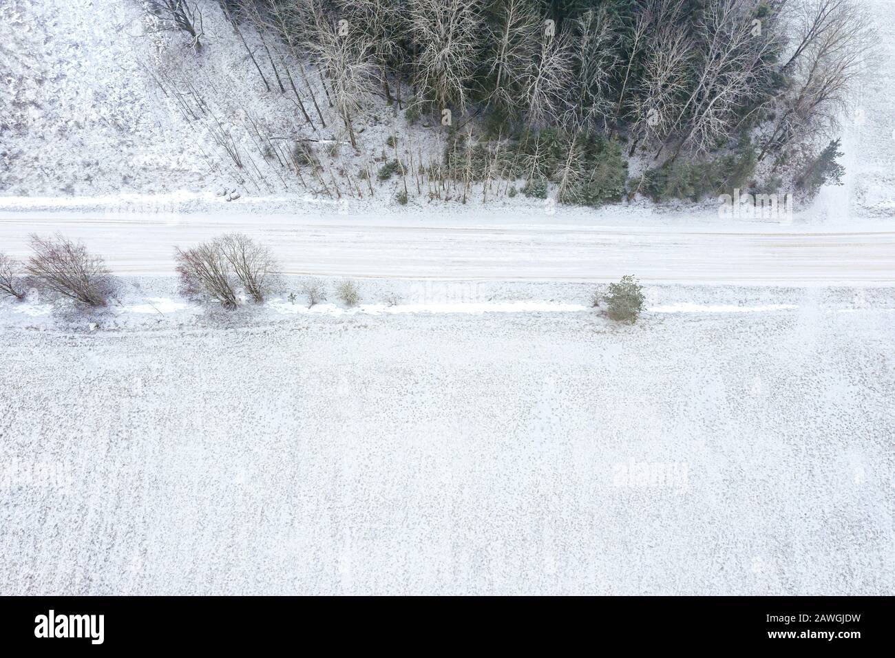 Landstraße und schneebedecktes Feld im Winter. Luftlandschaft in trübem Nebeltag Stockfoto