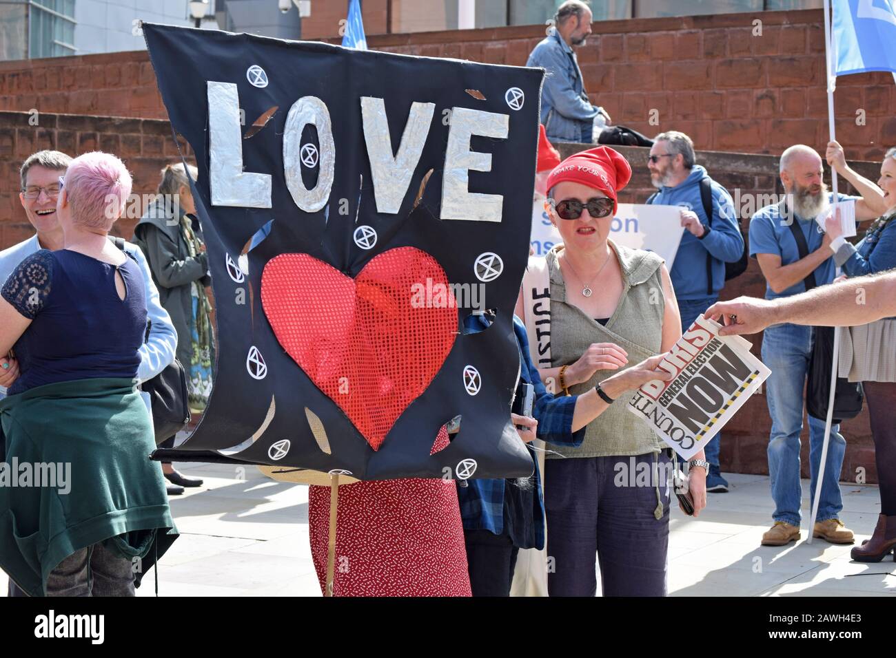 Starten Sie die Demokratie-Kundgebung am 200. Jahrestag des Peterloo-Massakers am Petersplatz Manchester neu. Frau, die mit Liebe und Herz Banner hält. Stockfoto