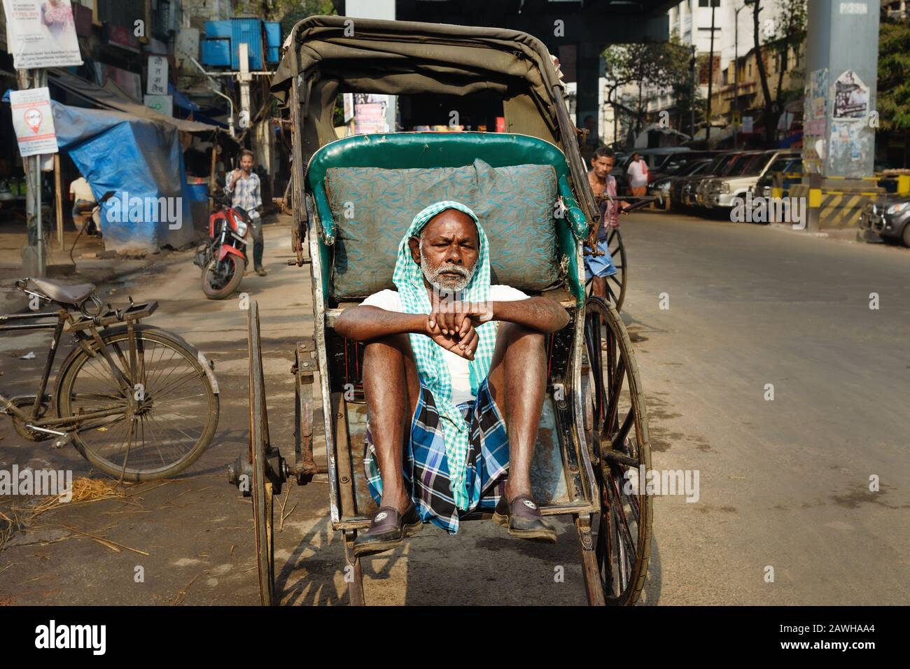 Indischer Rikscha-Puller, der auf seiner Rikscha sitzt und auf Passagiere in Kolkata wartet. Indien Stockfoto